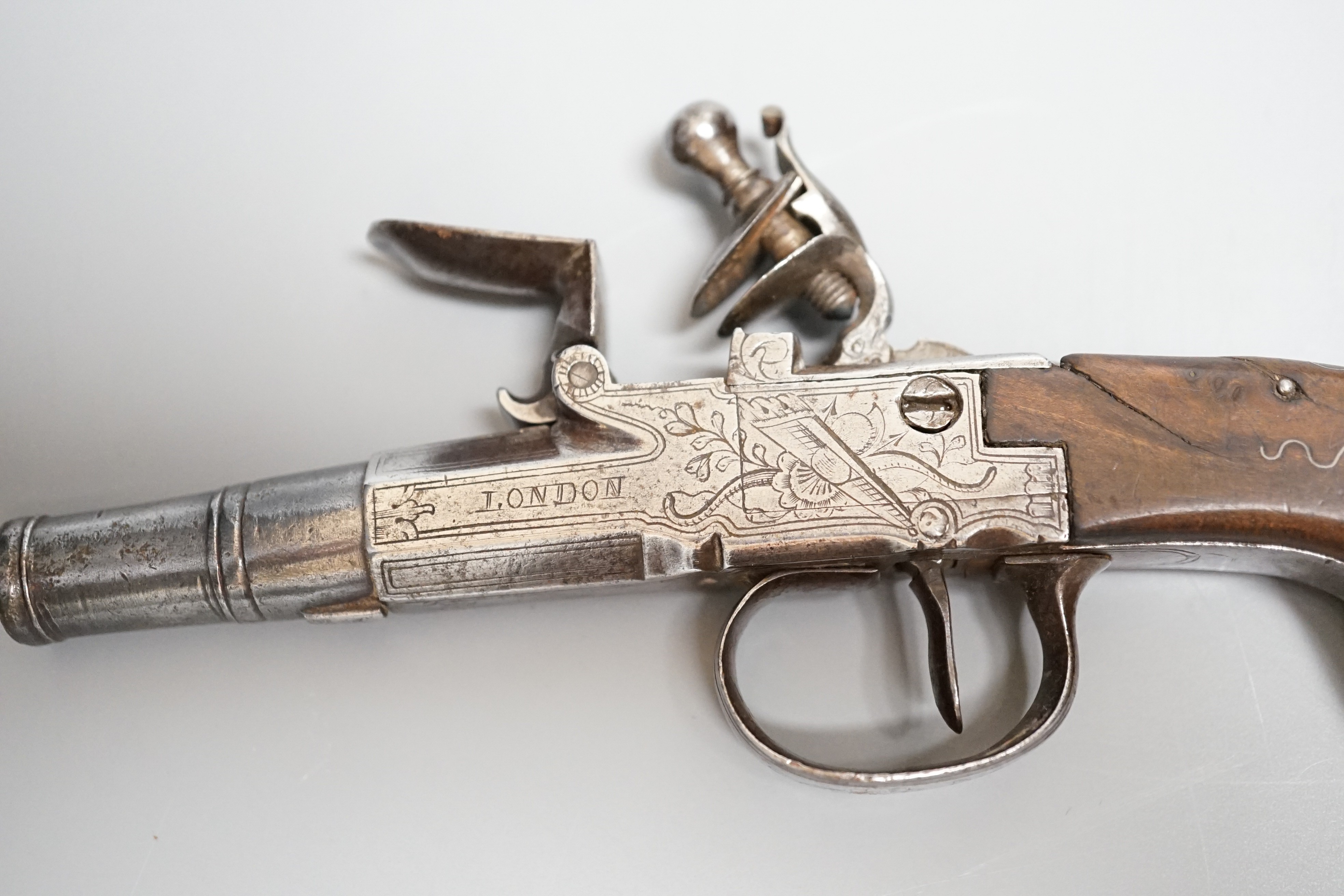 A Flintlock pocket pistol signed Segallas London, c.1770, turn off barrel, signed action engraved with trophies, trigger guard slides to lock mechanism, walnut grip with silver wire inlay, length 16.5cms.